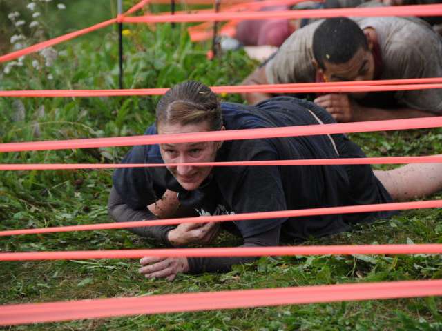 Doing army crawls underneath a low obstacle at the mud run. 