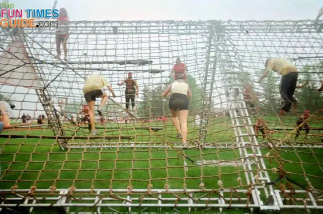 Climbing up and down cargo nets obstacle at the mud run. 